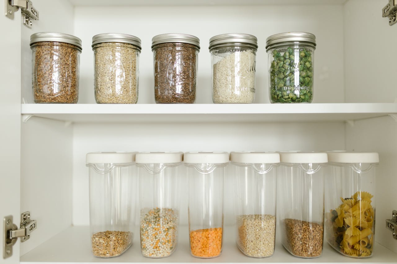 Home Neatly arranged pantry showcasing grains in glass jars and dry goods in plastic containers.